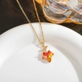 Macro view of gradient red-yellow maple leaf crystal pendant on a gold chain - Orange Red