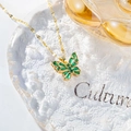 Macro shot of gold butterfly necklace with green gemstone on ice-cracked glass tray - Hollow Butterfly Necklace / Peacock Green