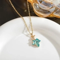 Detail shot of a vintage gold maple leaf pendant necklace with blue crystal and zircon in a bowl - Lake Blue