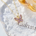 Elegant gold butterfly necklace featuring vibrant purple zircon stones on a white stone base - Purple