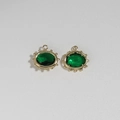 Detailed macro view of two oval gold stainless steel evil eye pendants with green stones - Green