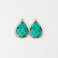 Detailed macro view of teardrop emerald faceted gemstones with gold plated bezel frame - Green