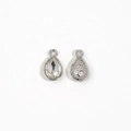 Detailed view of silver teardrop crystal charm with a pear-cut stone and textured back - White