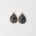 Detailed close-up of faceted grey glass teardrop pendants with gold plated metal edges - Gray