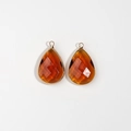 Macro detail of amber orange faceted teardrop pendant with gold rim for DIY jewelry - Burgundy