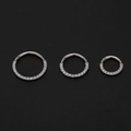 Detailed view of three stainless steel hinged rings with cubic zirconia inlay on black background - Large / Silver