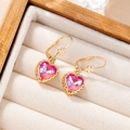 Close-up of heart-shaped crystal earrings with gold wavy edges in a beige jewelry box - Mocha Pink