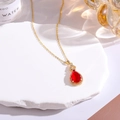Macro view of gold plated teardrop necklace with red faux jade and sparkling diamonds - Red