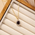 Elegant purple teardrop pendant necklace with white crystals on beige velvet jewelry box - Violet