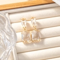 Detail view of pear and emerald cut crystal earrings on a velvet jewelry display - White