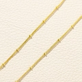 Macro shot of 18k gold plated satellite chain detail on textured leather background - Gold Bead Chain