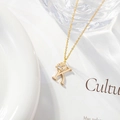 Golden necklace with letter K pendant and zircon flower accent on white background - Letter K