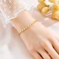 Close-up of gold titanium clover bracelet on wrist with elegant lace cuff and dried flowers - Gold