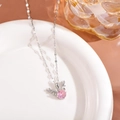 Close-up of silver elk necklace with a round pink gemstone and sparkling antlers on white plate - Choker Necklace / Pink