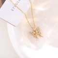 Macro view of gold butterfly pendant featuring intricate hollow wings and zircon inlay - White