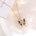 Detailed close-up of golden butterfly necklace with blue marquise-cut zircon stones - Medium Blue