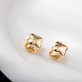 Primo piano di orecchini a trifoglio dorati su piatto bianco con finitura a specchio lucida - 14x14mm / Oro