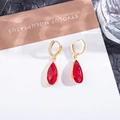 Dettaglio macro di orecchini a goccia rossi con cerchi dorati decorati con strass - Rosso