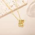 Dettaglio macro della collana con ciondolo lettera E dorata e zirconi su pietra beige - Stile Lettera E (E)
