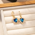 Detailed macro view of heart-shaped blue crystal earrings with gold plating and white zircons - Gold Plated Blue Gem Earrings Pair