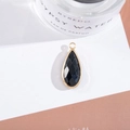 Macro shot of a black pear-shaped crystal pendant with gold plating on a white background - Outer Size 11x25mm / Black