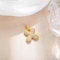Macro view of a 3D gold cross pendant with micro-paved white zircons on a beige background - Letter X (BGQZM003)