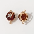 Detailed macro view of a gold-plated flower connector with a red gemstone for jewelry making - Dark Red