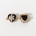 Macro view of heart-shaped gold alloy jewelry connectors with black gemstones and flower detail - Black