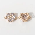 Macro detail of heart crystal connector with floral gold base for DIY jewelry making - White
