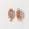 Macro-opname van vergulde rozenbedeltjes met roze kristallen en lussen voor DIY-sieraden - Roze