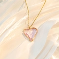 Details einer rosafarbenen Herz-Kristallkette mit Goldkette auf weißer Seide - Rosa