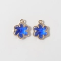 Detailed close-up of 12mm gold-plated six-petal flower pendants with deep blue crystals - Sapphire Blue