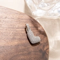 Detailed macro view of silver letter L pendant with pavé cubic zirconia on wooden surface - L