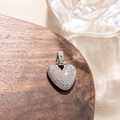 Macro shot of silver heart pendant with micro-paved zircons on elegant wooden tray - Letter V