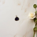 Macro shot of purple faceted teardrop pendant with gold bezel on marble surface - Deep purple