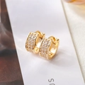 Close-up of wide gold-plated hoop earrings featuring micro-paved triple rows of cubic zirconia - Gold