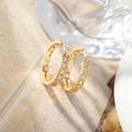 Close-up of gold-plated hoop earrings with micro-pave zircons on a marble background - Gold