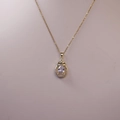 Detailed close-up of a pear-cut crystal teardrop pendant with a delicate bow design - Gold With Transparent Stone And Bowknot