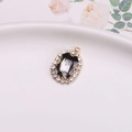 Vintage oval gold pendant featuring a dark center stone with sparkling crystal accents - Gray