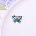 Vista detallada de un colgante de mariposa dorado con alas de cristal azul facetado - Azul lago