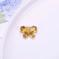 Detalle macro del colgante de mariposa en cristal ámbar con chapado en oro - Dorado
