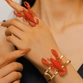 Vista dettagliata di un anello a forma di aragosta rossa e bracciale dorato sulla mano - Bracelet and Ring Set / Set di 2 pezzi / Oro