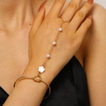 Detailed shot of gold slave bracelet with white flower charm and delicate pearls on hand - 63kc Gold 0270 (flower)