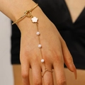 Gold slave bracelet with white floral charms and faux pearls on a model hand - 花朵珍珠连指手链(0270) / KC Gold