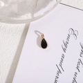 Minimalist black water drop pendant with gold plated border on a decorative background - Black