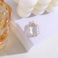 Close-up van een rechthoekige kristallen hanger met goud vergulde rand op een witte voet - Wit