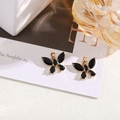 Detailed close-up of golden butterfly charms with black crystals and hanging loop - Black