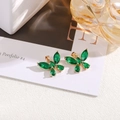 Close-up of gold-plated butterfly pendants with green marquise stones on a white block - Peacock Green
