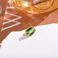 Detailed macro view of an oval green zircon earring with a gold-plated four-prong setting - Grass Green