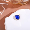 Macro shot of triangle dark blue crystal pendant with gold rim on white stone base - Large / Medium Blue & White